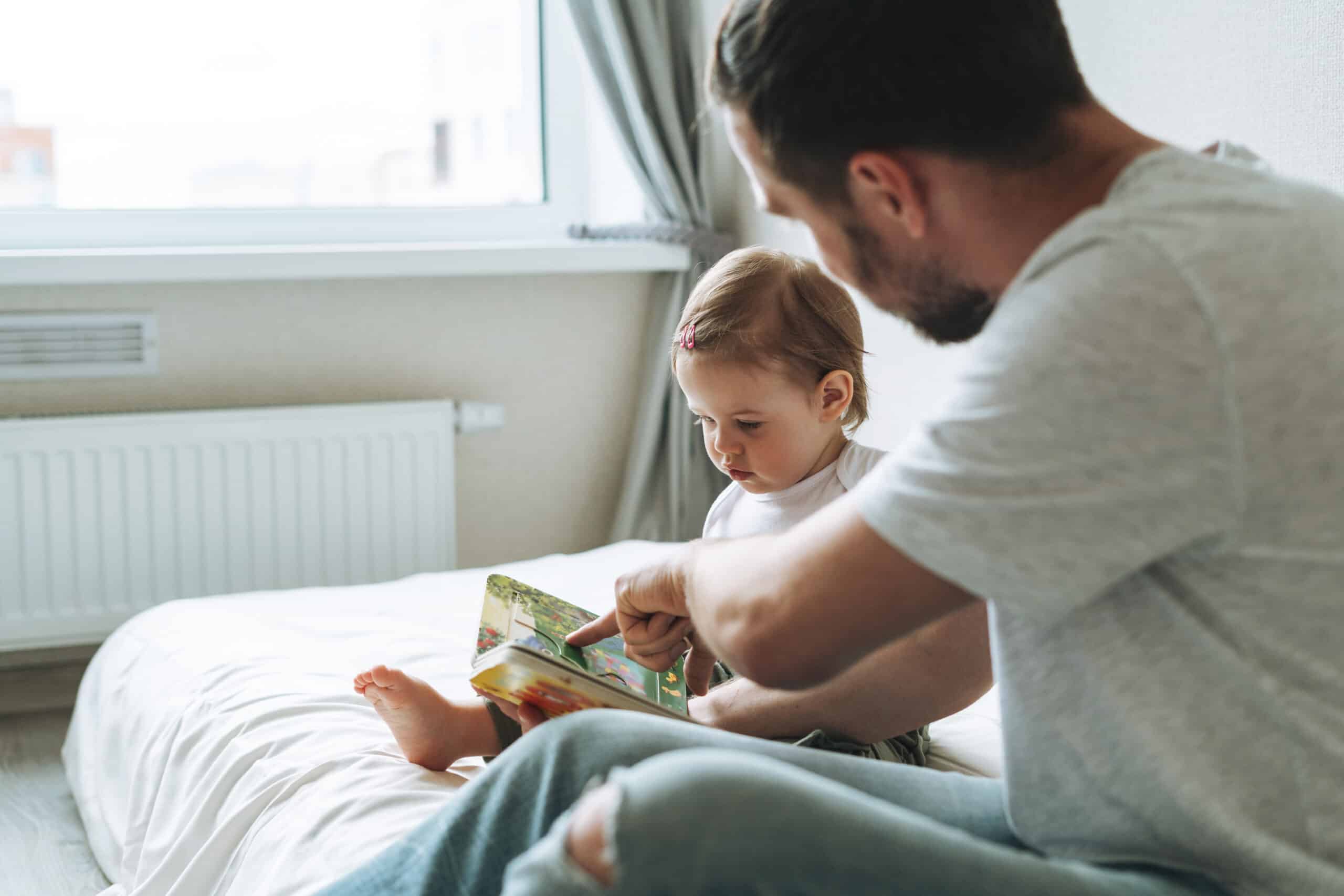 Vater mit Tochter auf Bett: Nur wenige Väter nehmen ein Jahr Elternzeit. Foto: Adobe Stock / Galina Zhigalova