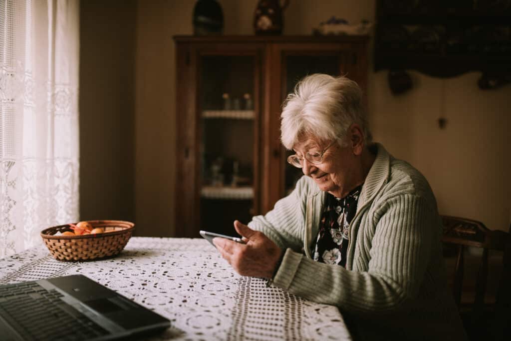 Seniorin am Tisch mit Smartphone: Laut Studien fühlen sich viele Menschen von der Digitalisierung abgehängt.