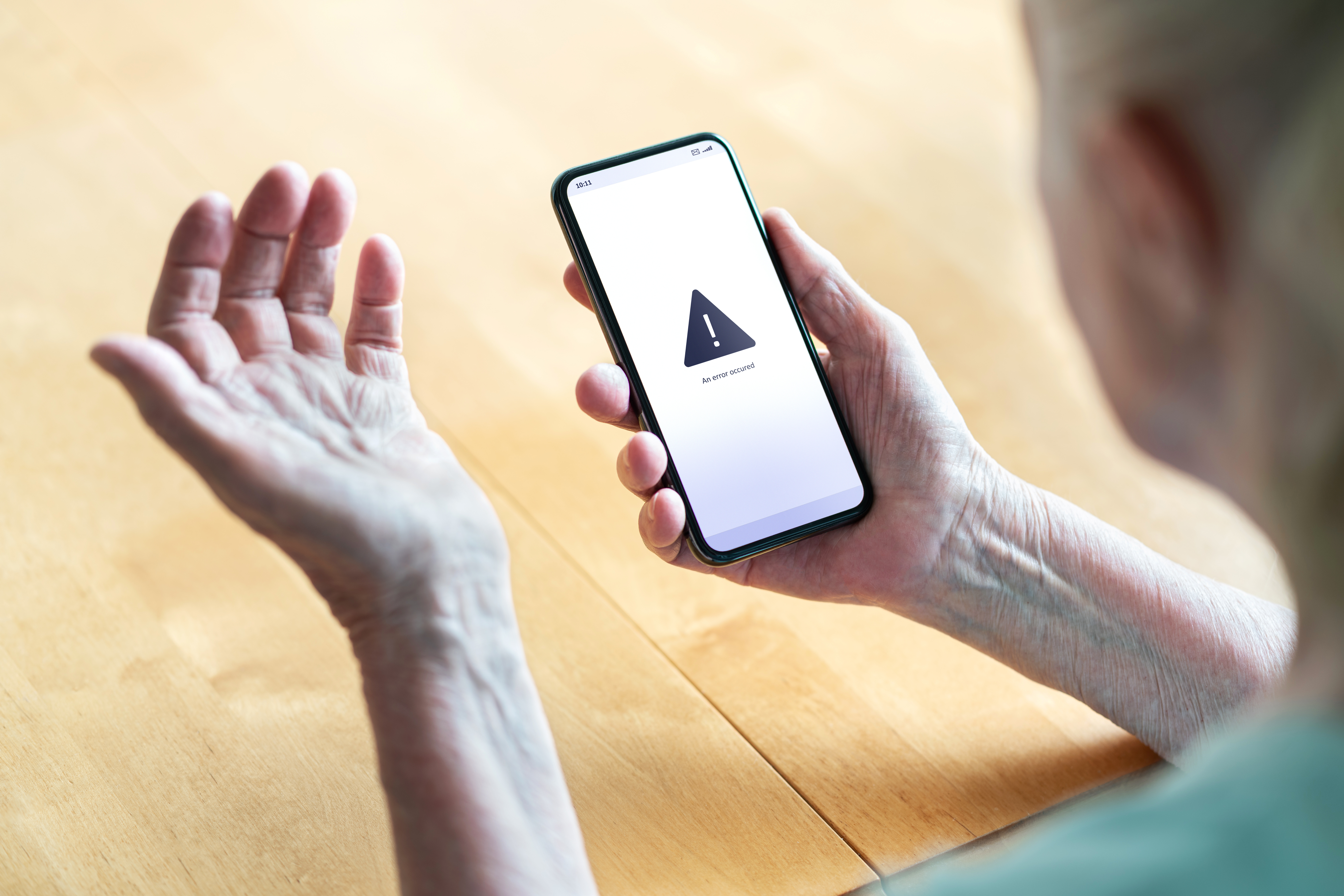 Seniorin mit Smartphone, das eine Fehlermeldung anzeigt: Viele Menschen kommen mit der Digitalisierung nicht zurecht.